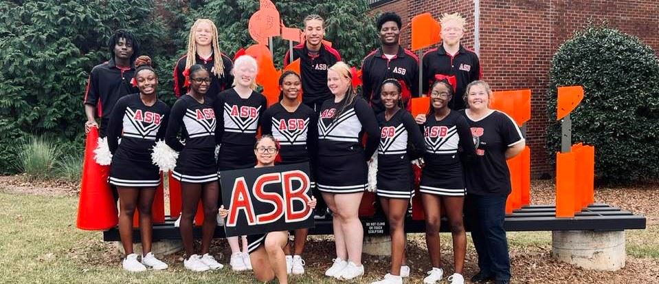  The cheer squad pose as a group and smile to the camera.